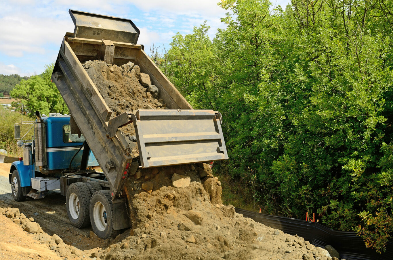 Road Dump A 10 yard dump truck dumps its load of rock and soil on a new road construction project